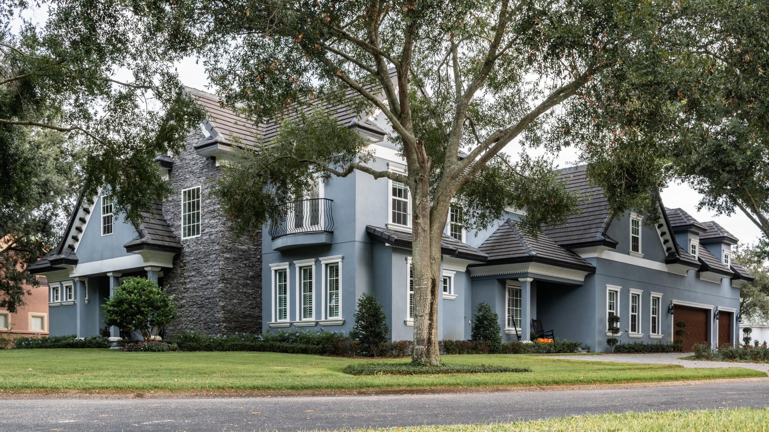 Corner view of a custom home with a stone-clad front element, balcony and long garage-side elevation.
